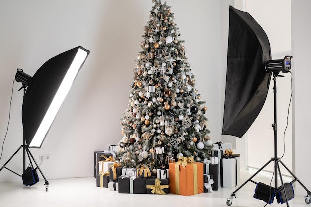 Árvore de Natal no estúdio de fotografia interior branco com elegante caixa de presente preta e laranja em pé como modelo com luz de flash