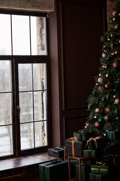 Árvore de Natal no interior de casa perto de uma grande janela em alta chave Apresenta caixa perto da árvore decorada