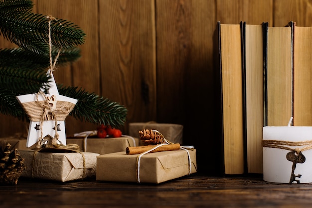 Árvore de Natal, presentes, livros, estrela artesanal em uma mesa de madeira.