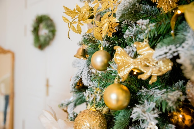 Árvore de natal ricamente decorada com ornamentos douradosÁrvore de natal com uma guirlanda de enfeites dourados e luz de velasfeliz ano novo Foco seletivo