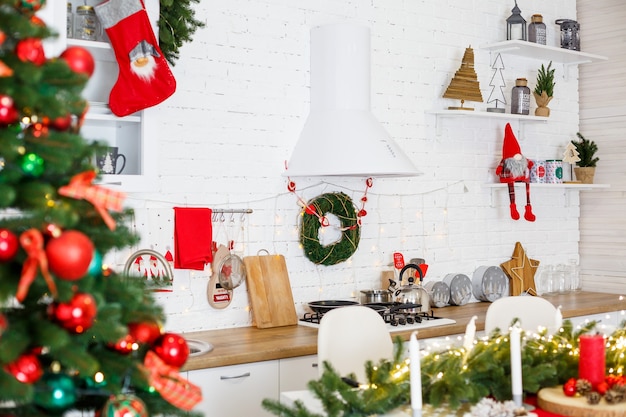 Árvore de Natal verde, decorada com bolas, enfeites de Natal, guirlandas amarelas. Decorações de ano novo na cozinha. Ano Novo. Decorações da casa para o Natal.