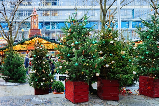 Árvores de Natal no mercado de Natal na Igreja Memorial Kaiser Wilhelm em Winter Berlin, Alemanha. Decoração da Feira do Advento e Barracas com Artigos de Artesanato no Bazar.