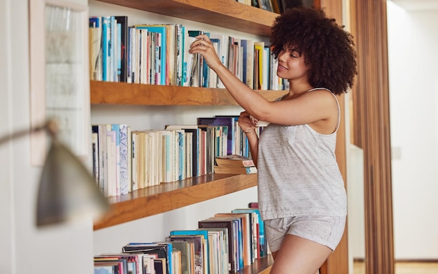 Árvores tatuadas para um mundo em um fichário Foto de uma jovem atraente navegando em uma estante de livros em casa