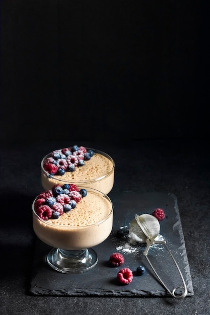 Ryazhenka (fermentierte gebackene Milch) Mousse in Glasschalen mit frischen Beeren dekoriert. Platz kopieren