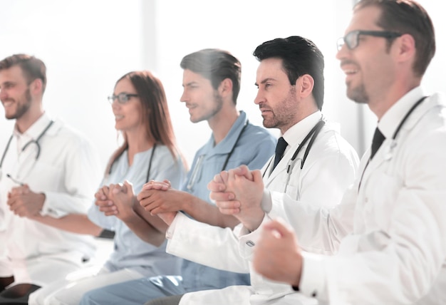 Ärzte sitzen in einer Reihe und halten sich an den Händen