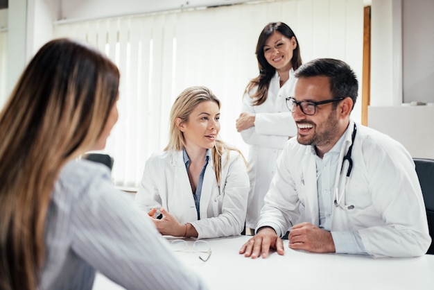 Ärzteteam, das einer Patientin gute Nachrichten erzählt.