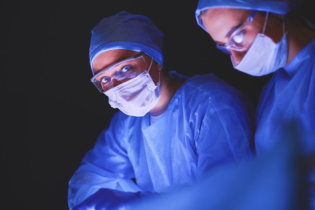 Ärzteteam in der Chirurgie vor dunklem Hintergrund