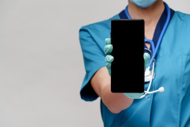 Ärztin der Krankenschwester mit Stethoskop, die Schutzmaske und Gummi- oder Latexhandschuhe trägt, die Handy halten