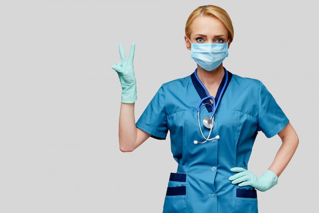Ärztin der Krankenschwester mit Stethoskop, die Schutzmaske und Gummi- oder Latexhandschuhe trägt