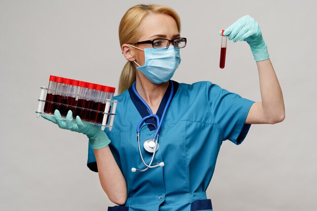 Ärztin des Arztes, die Schutzmaske und Handschuhe trägt - Haltegestell mit Virusbluttests