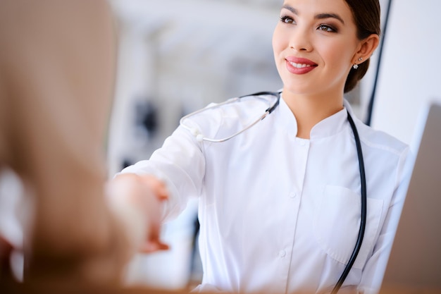 Ärztin, die dem Patienten im Büro die Hand schüttelt