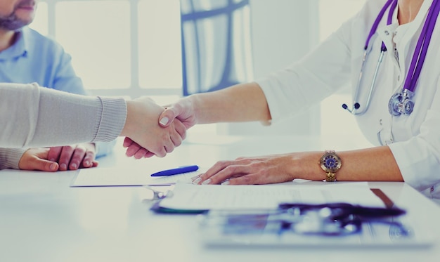 Ärztin, die eine Hand in ihrem Büro rüttelt