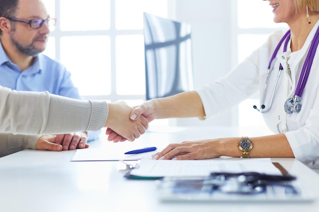 Ärztin, die eine Hand in ihrem Büro rüttelt