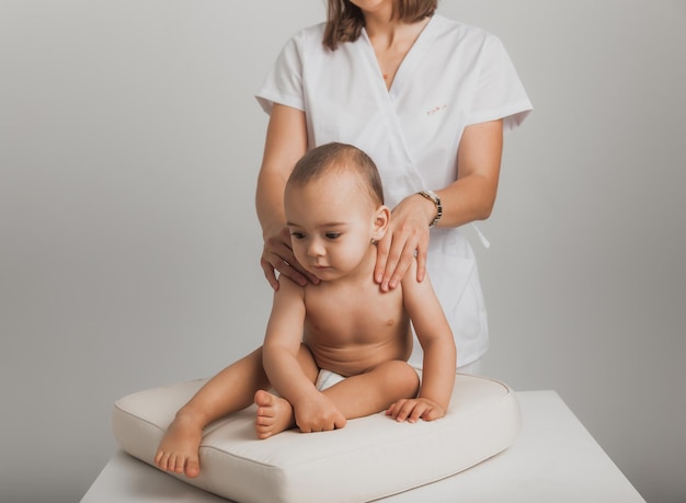 Ärztin, die einem einjährigen Baby Rückenmassage macht. Babymassagekonzept