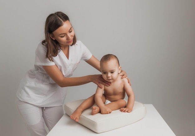 Ärztin, die einem einjährigen Baby Rückenmassage macht. Babymassagekonzept