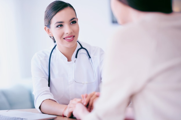 Ärztin hält die Hände und Stützen der Patientin. Medizin- und Gesundheitskonzept. Arzt und Patient