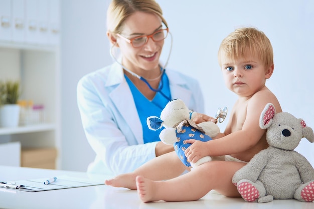 Ärztin hört Kind mit einem Stethoskop in der Klinik