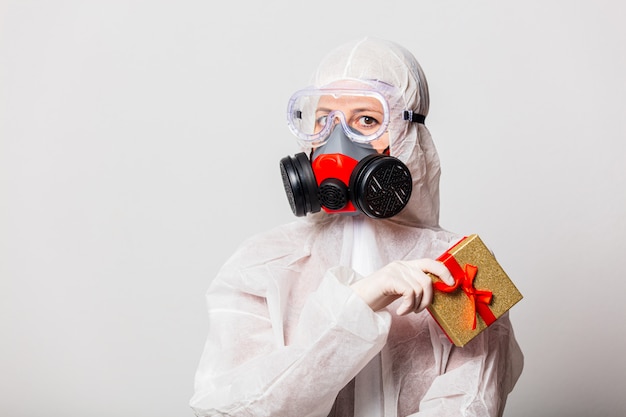 Ärztin im Schutzanzug und Brille mit Maske hält Geschenkbox