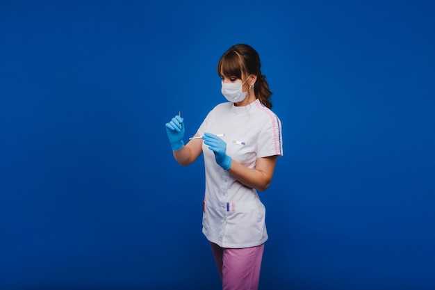 Ärztin in einer Maske und Handschuhen, die zeigen, wie man eine Pinzette in einer Arztpraxis auf weißem Hintergrund hält. Doktor liebt seine Arbeit mit Glück.