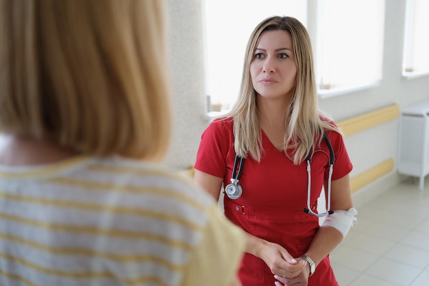 Ärztin in roter Uniform berät und hört Patienten in der Klinik zu