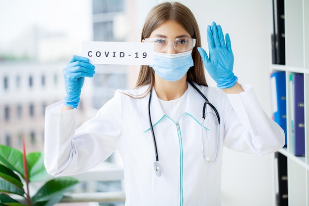 Ärztin in uniform mit einem papierschild mit der aufschrift covid