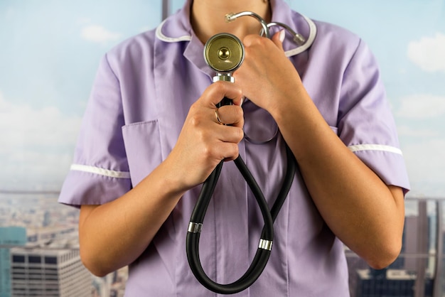 Ärztin in Uniform mit einem Stethoskop in den Händen auf dem Hintergrund eines Krankenhauses