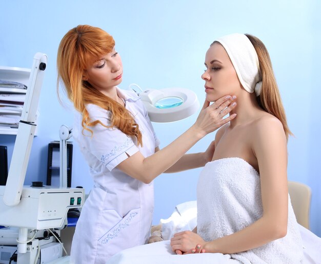 Ärztin Kosmetikerin, untersucht die Haut eines jungen Mädchens. Vorbereitung auf die Schönheitsbehandlung.