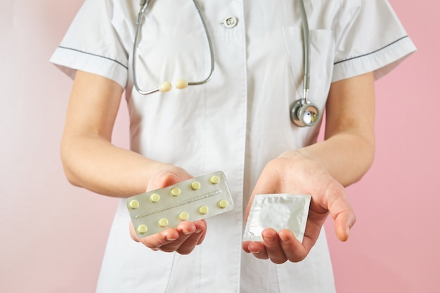 Ärztin mit Kondom zur Vorbeugung und Antibabypille. Verhütungsmittel in Händen für sicheren Sex