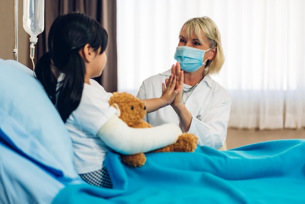 Ärztin mit Maske im Gespräch mit kleinem Patienten