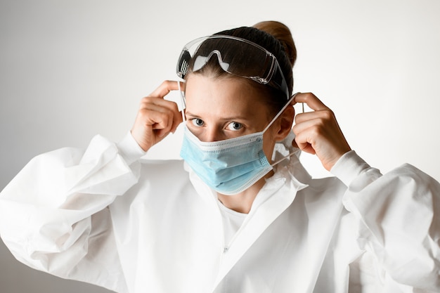 Ärztin mit Schutzbrille auf dem Kopf setzte medizinische Maske auf.