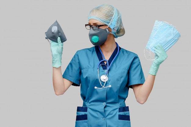 Ärztin mit Stethoskop, das Schutzmaske und Latexhandschuhe über hellgrauem Hintergrund trägt