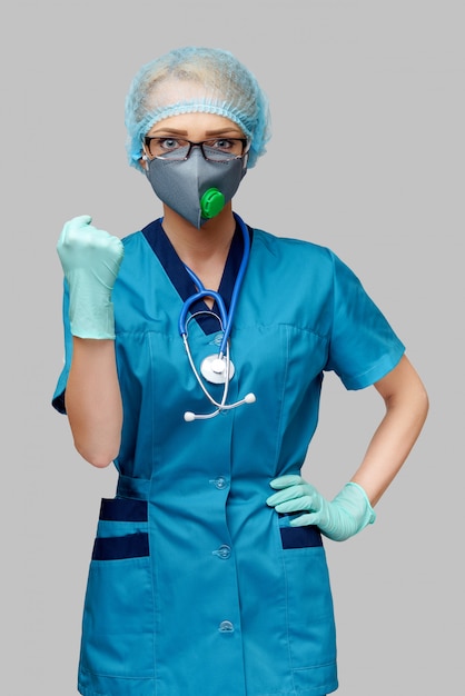 Ärztin mit Stethoskop mit Schutzmaske und Latexhandschuhen über hellgrauer Wand