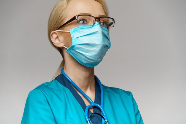 Ärztin mit Stethoskop mit Schutzmaske und Latexhandschuhen