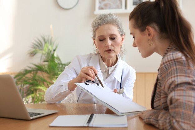 Ärztin mittleren Alters in Absprache mit dem Patienten im Büro.