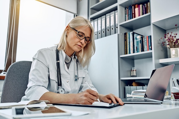 Ärztin schreibt Rezept in einem hellen Büro Gesundheitswesen und medizinisches Konzept Niedriger Winkel