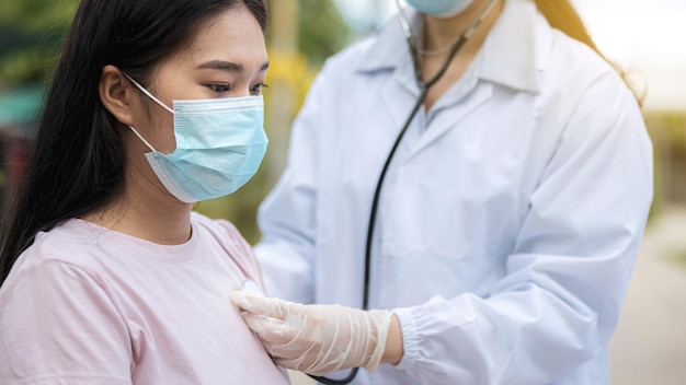 Ärztin untersucht Frau mit Stethoskop auf Coronavirus-Pneumonie-Schilder, die Brust der Frau im Feldkrankenhaus überprüfen.