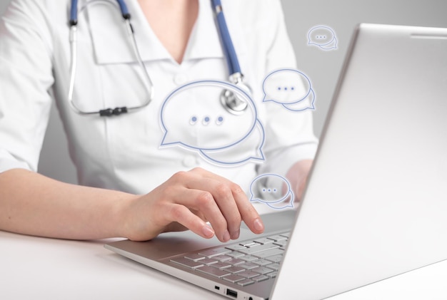 Ärztliche Online-Beratung Arzt, der einen Laptop verwendet, um aus der Ferne mit Patienten zu chatten und Antworten auf allgemeine Gesundheitsbedenken zu geben Frau mit Stethoskop, die mit Computer am Tisch sitzt