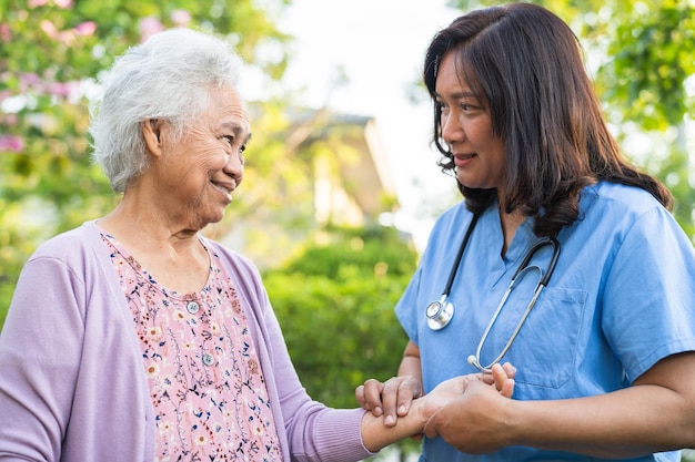 Ärztliche Pflegekraft Hilfe und Pflege Asiatische ältere Patientin geht mit Walker im Park im Krankenhaus spazieren