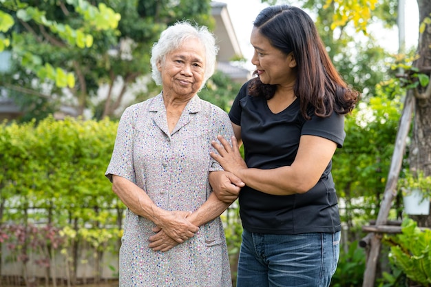 Ärztliche Pflegekraft Hilfe und Pflege Asiatische Seniorin, die im Krankenhaus im Park spazieren geht