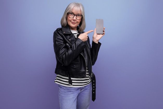 S moderna blogueira velha com cabelos grisalhos usa a internet de um smartphone em um fundo brilhante
