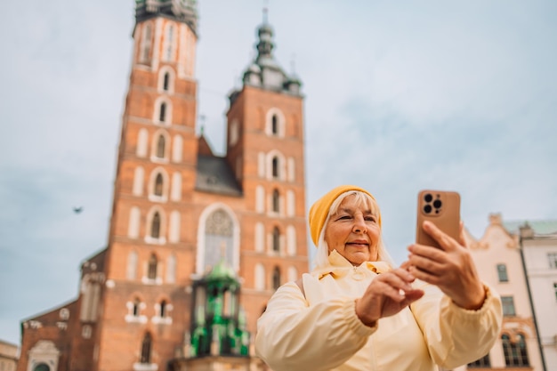 S mulher turista velha tirando selfie no smartphone se divertindo fazer uma foto selfie na praça do mercado em