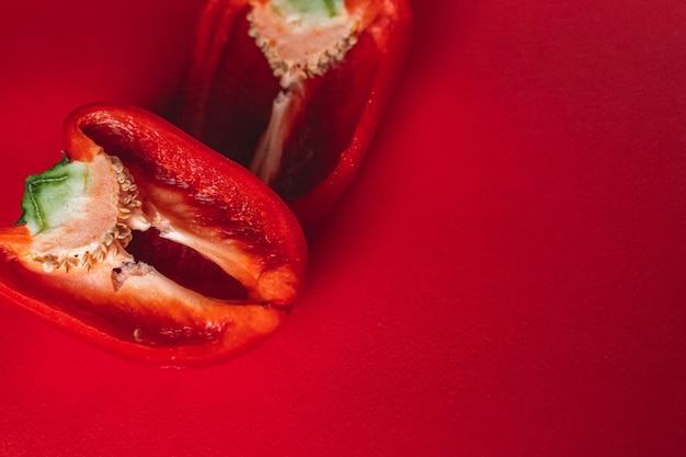 SÜßER frischer ROTER PFEFFER AUF EINEM ROTEN HINTERGRUND halbiert Foto für das Menü richtige Ernährung frisches Gemüse