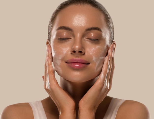 Foto sabão de lavagem de máscara facial de mulher fecha a pele limpa. cor de fundo marrom