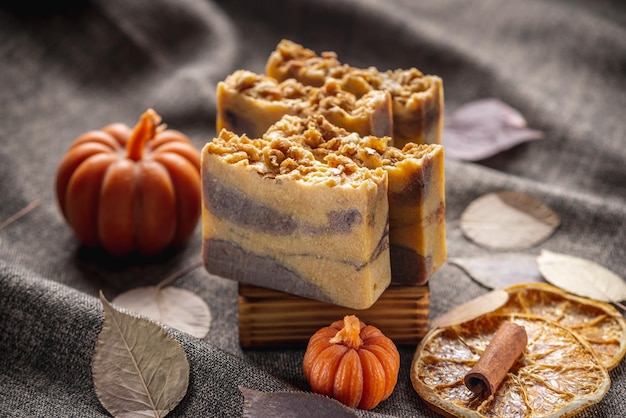 Sabón natural perfumado hecho a mano y velas en forma de calabaza sobre un fondo oscuro con hojas secas amarillas para crear una atmósfera acogedora Hermosa postal de otoño