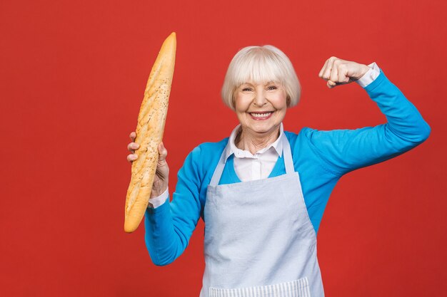 Sabor de Francia. Retrato de una mujer senior alegre sosteniendo un delicioso pan baguette delicioso