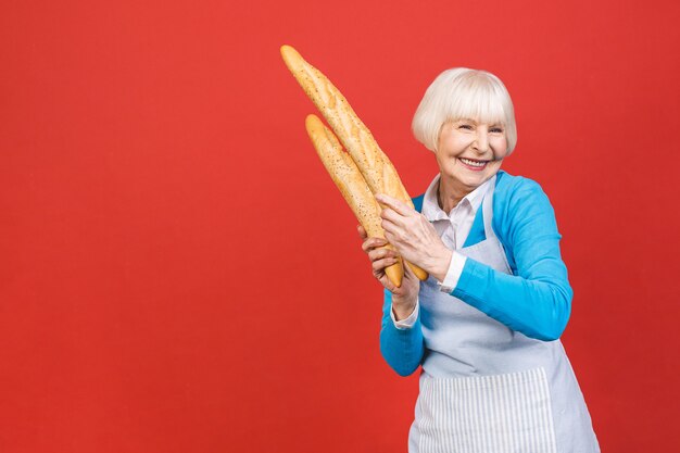 Foto sabor de francia. retrato de una mujer senior alegre sosteniendo un delicioso pan baguette delicioso