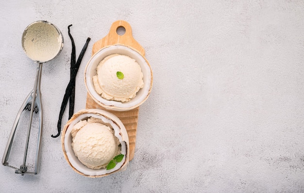 Sabores de helado de coco en la mitad de la configuración de coco sobre fondo de piedra blanca. Concepto de menú de verano y dulces.