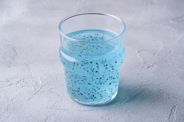Saborosa bebida de cor azul com sementes de chia de manjericão em vidro, bebida saudável de verão, mesa de concreto de pedra, vista angular