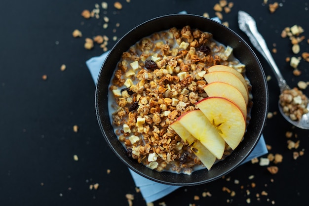 Saborosa granola de muesli frutada caseira servida em uma tigela em fundo escuro. fechar-se