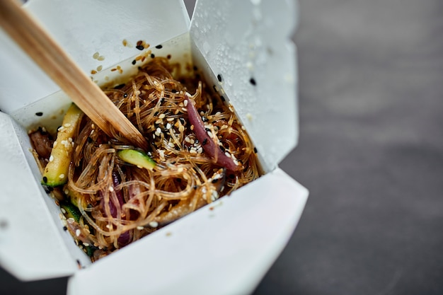 Saborosa massa de macarrão Udon com tempuru, camarão wok em caixa e palitos de madeira, comida japonesa apimentada